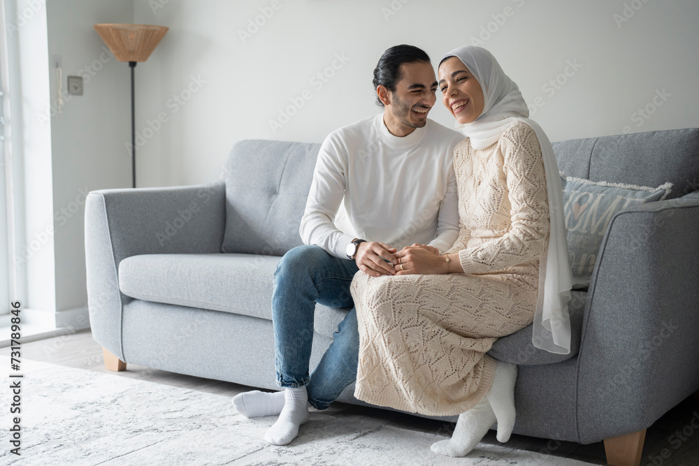 Smiling mid adult couple holding hands on sofa Smiling mid adult couple holding hands on sofa