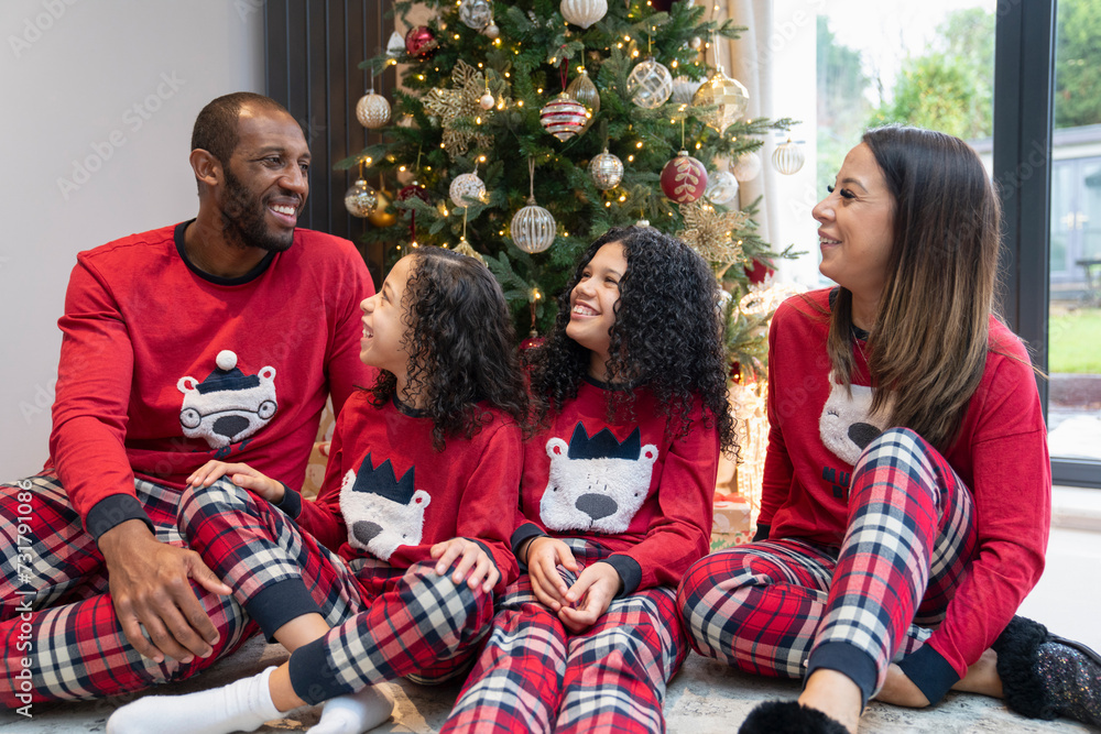Portrait of smiling parents with two daughters in front of Christmas tree Portrait of smiling parents with two daughters in front of Christmas tree
