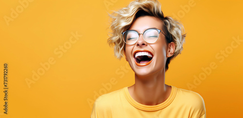 Portrait of a young laughing woman with blond short hairstyle. Isolated over yellow background.
