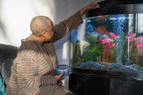 Photography Mature woman feeding fish in aquarium