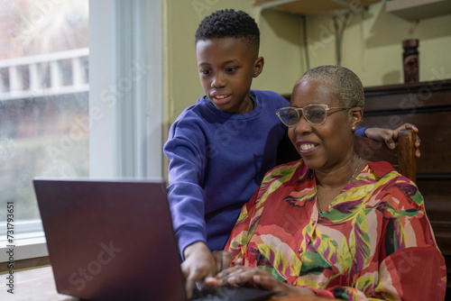 Grandmother with grandson using laptop at home 