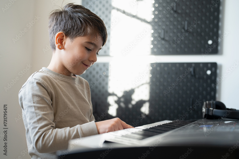 Fototapeta premium Boy (6-7) playing music keyboard at home