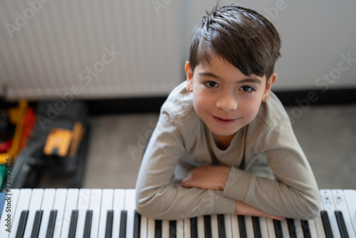 Portrait of boy (6-7) playing music keyboard at home