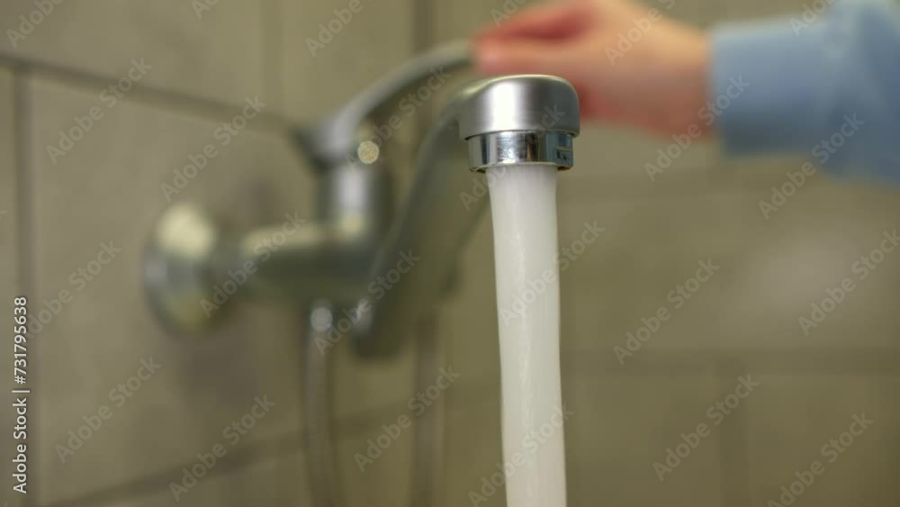 Female hand opening the faucet in the bathroom. close up video water pouring from a faucet tap slow motion. The strong water pressure flowing from a stylish chrome tap indoors Female hand opening the faucet in the bathroom. close up video water pouring from a faucet tap slow motion. The strong water pressure flowing from a stylish chrome tap indoors