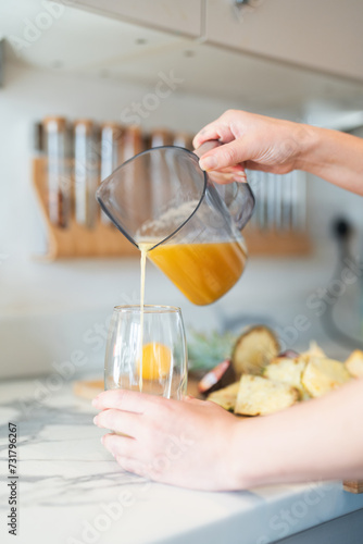 Woman in kitchen, pouring freshly made smoothie