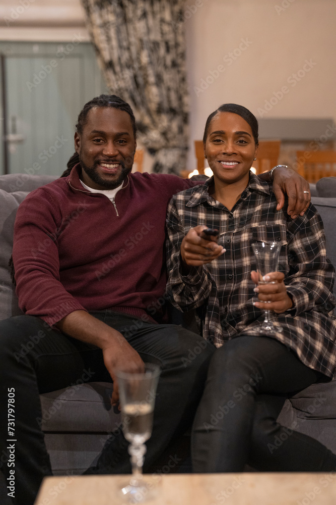 Fototapeta premium Mid adult couple sitting on sofa and drinking wine