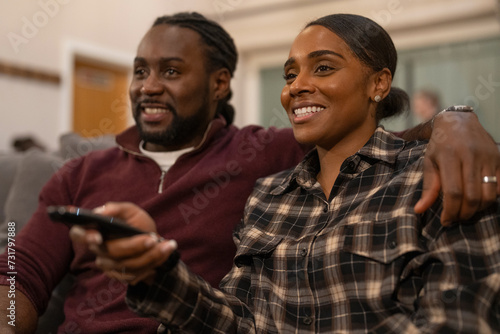 Mid adult couple sitting on sofa and watching TV © Cultura Creative