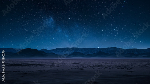 Desert with distant mountains under a starry night sky