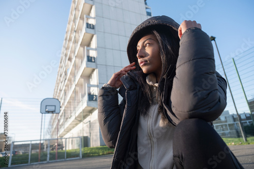 Bilde på lerret Portrait of woman in black overcoat with hood outdoors