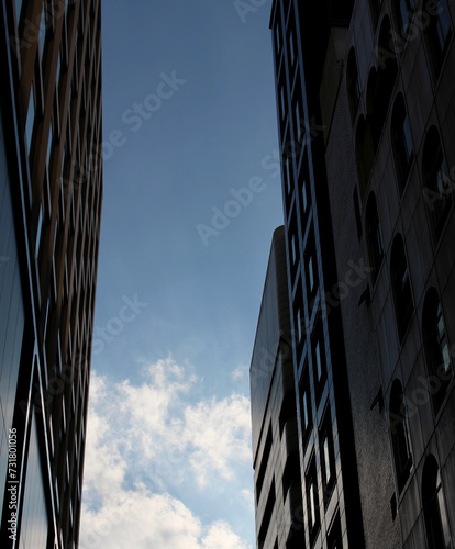 Modern buildings with blue sky, contrast between bright clouds and shadowed buildings