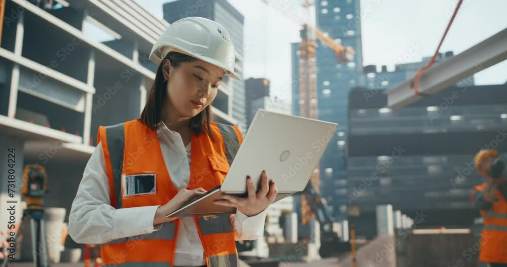 Portrait of a Beautiful Japanese Female Civil Engineer Working on a Laptop at a Construction Site. Young Asian Woman Standing Outdoors, Using Computer for Planning and Developing a Real Estate Project Portrait of a Beautiful Japanese Female Civil Engineer Working on a Laptop at a Construction Site. Young Asian Woman Standing Outdoors, Using Computer for Planning and Developing a Real Estate Project