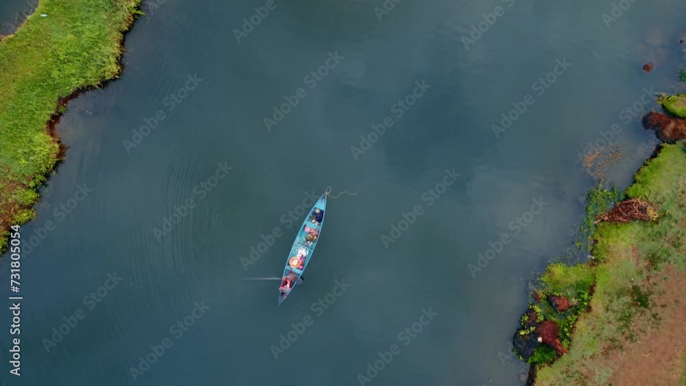 Raising drone over a fishing boat in the lake with green swamp land Raising drone over a fishing boat in the lake with green swamp land