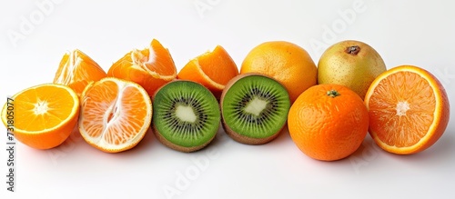 A variety of fruits including oranges, kiwi, and apples are arranged in a row on a white surface, showcasing a natural and colorful selection of food.