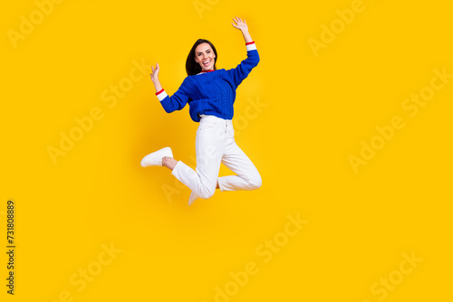 Full body size photo of energetic funky woman in blue knitted pullover jumping careless at friday party isolated on yellow color background