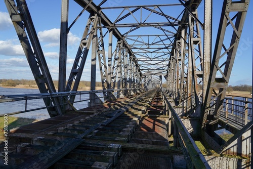 a railroad track crosses an old steel bridge across a waterway