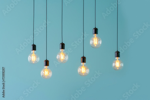 Hanging glowing light bulbs, idea on light blue background. 