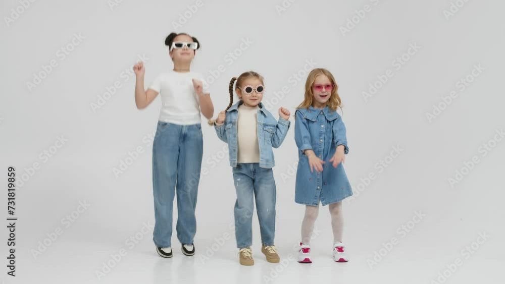 A group of modern, happy children are dancing and having fun on a light isolated background. Concept for clothing advertising, children's shopping and style. A group of modern, happy children are dancing and having fun on a light isolated background. Concept for clothing advertising, children's shopping and style.