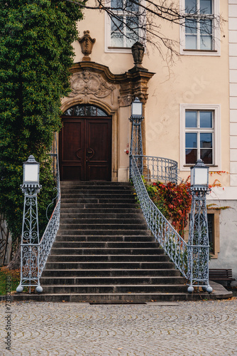 The main entrance to the palace in Krzyzowa with stairs and lanterns and vines in autumn colors.