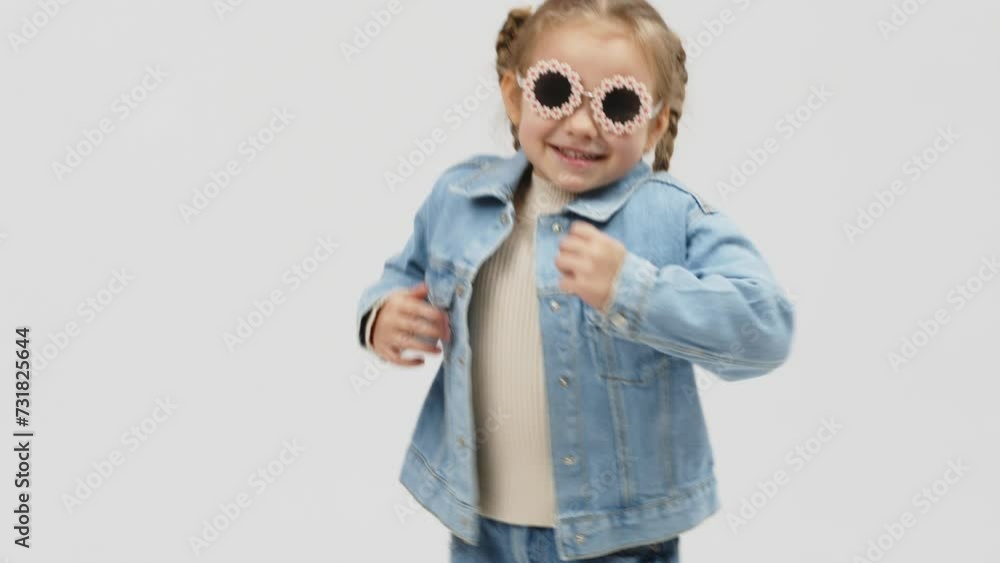 Cheerful little girl in modern clothes having fun, performing freestyle dance moves, on isolated white background. Children's clothing advertising concept Cheerful little girl in modern clothes having fun, performing freestyle dance moves, on isolated white background. Children's clothing advertising concept