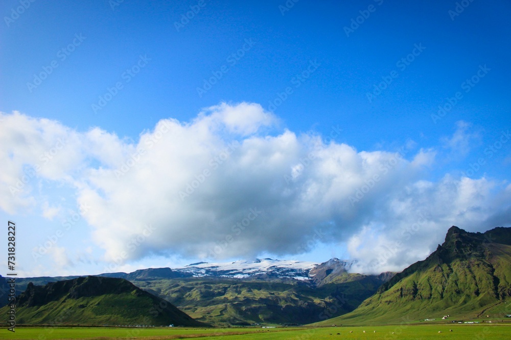 Scenic landscape of a green field in front of a majestic backdrop of mountains