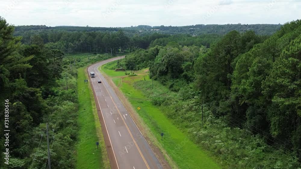Aerial of the traffic on the road in the middle of the dense green forest Aerial of the traffic on the road in the middle of the dense green forest