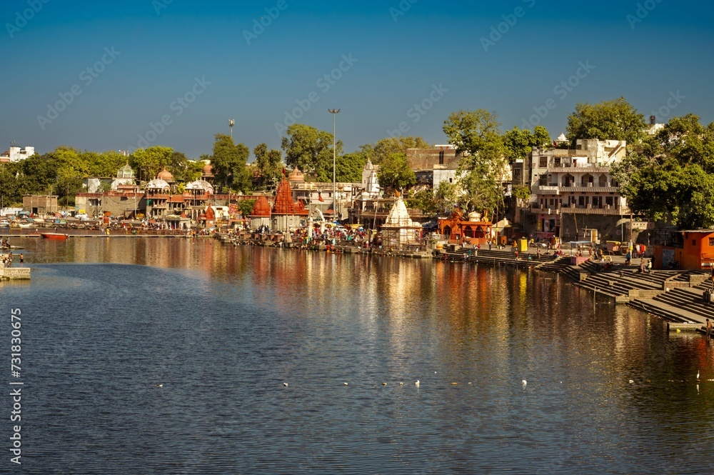 Scenic view of a tranquil river with various small boats and houses in Ujjain, Ram Ghat