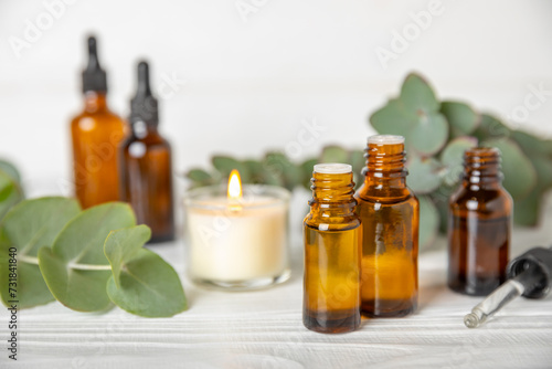 Fototapeta Naklejka Na Ścianę i Meble -  Eucalyptus essential oil in a glass bottle with green eucalyptus leaves on a textured wooden background. Aromatherapy concept. Spa. Natural organic ingredients for cosmetics and body care.Copy space