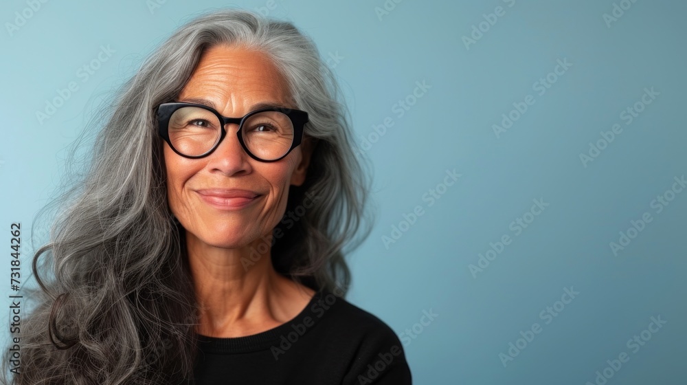 Woman with gray hair wearing glasses smiling against a blue background. Woman with gray hair wearing glasses smiling against a blue background.