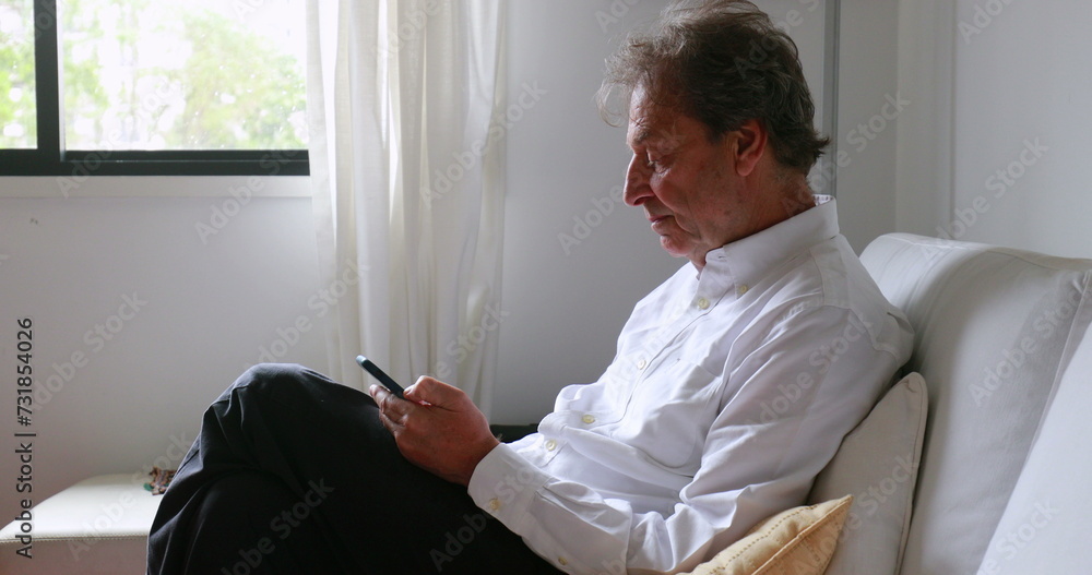 Older man looking at cellphone device at home sofa Older man looking at cellphone device at home sofa