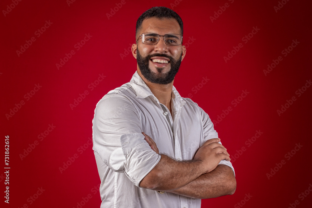Man, with a beard, wearing glasses, with a white shirt, with various facial expressions, on a red studio background Man, with a beard, wearing glasses, with a white shirt, with various facial expressions, on a red studio background