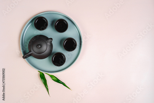 Black teapot and cups with bamboo leaves on a tray. Traditional tea ceremony. photo