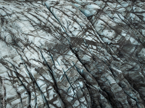 Ice terraces of glacier tongue, rough surface with crack pattern dirty white color, aerial directly above view. Nature, background and design concepts.