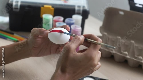 hands of a dark-skinned Latina artisan woman, painting Easter eggs with brushes and acrylic paints