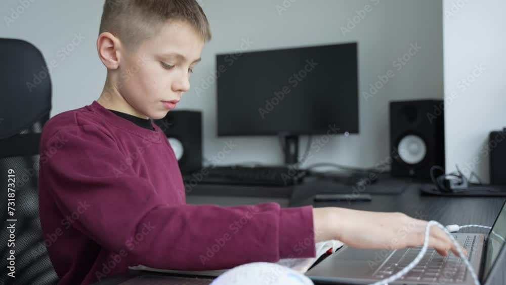 Young smart boy doing his homework at home. Schoolboy preparing for online classes at home during quarantine at school. Caucasian boy using laptop. Young smart boy doing his homework at home. Schoolboy preparing for online classes at home during quarantine at school. Caucasian boy using laptop.