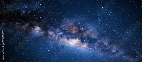 The Milky Way galaxy, an astronomical object, is visible in the night sky filled with electric blue atmosphere and scattered clouds.