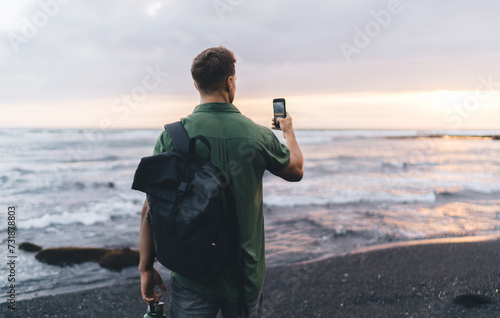 Male traveler taking photo of sunset over sea