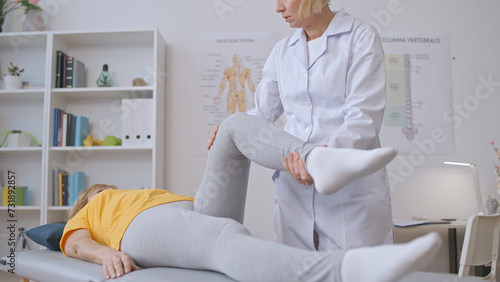 A woman orthopedist assesses a patient's leg after successful treatment in her clinic office