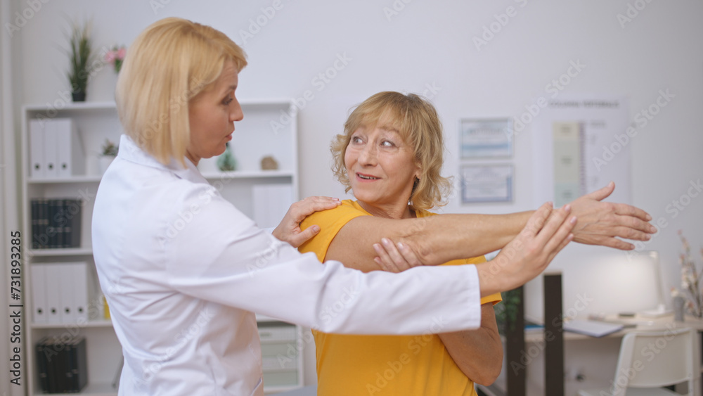 A senior patient and a rehabilitation doctor perform a stretching exercise together A senior patient and a rehabilitation doctor perform a stretching exercise together