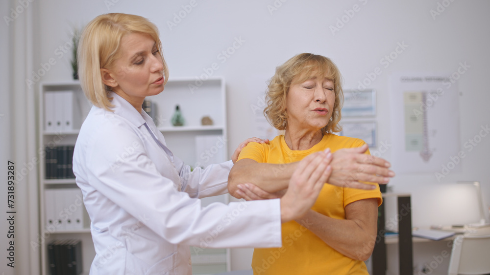 Fototapeta premium A senior woman endures difficulties while doing rehabilitation exercises with a doctor in a clinic