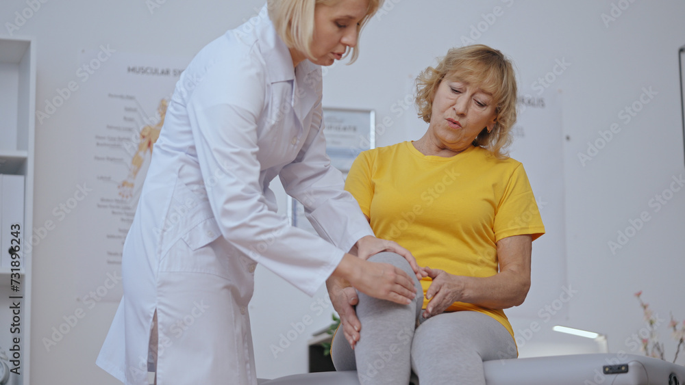 Obraz premium A patient feels pain in her knee during a doctor's examination at a rehabilitation clinic