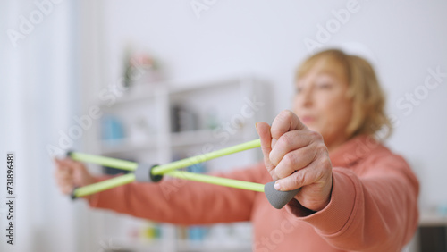 A senior woman exercises with a stretching band, committed to an active lifestyle and fitness at home photo