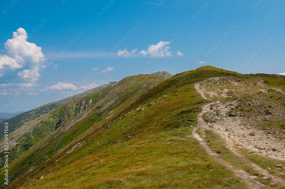Road to Mountain Chopok in Low Tatras (Nízke Tatry, Demänovská Dolina). National Park with Mountain Hut and Cableway in central Slovakia. Hiking along a mountain ridge in clear weather. Road to Mountain Chopok in Low Tatras (Nízke Tatry, Demänovská Dolina). National Park with Mountain Hut and Cableway in central Slovakia. Hiking along a mountain ridge in clear weather.