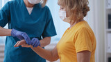 Close-up of a traumatologist in a mask monitoring the healing process of her patient