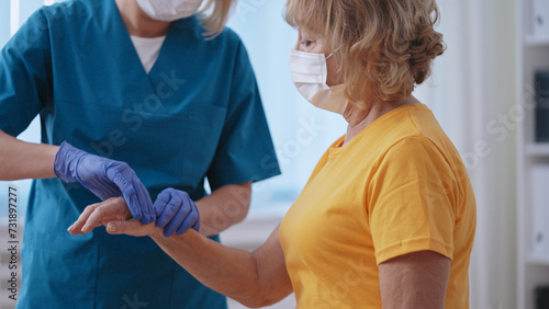 Close-up of a traumatologist in a mask monitoring the healing process of her patient photo