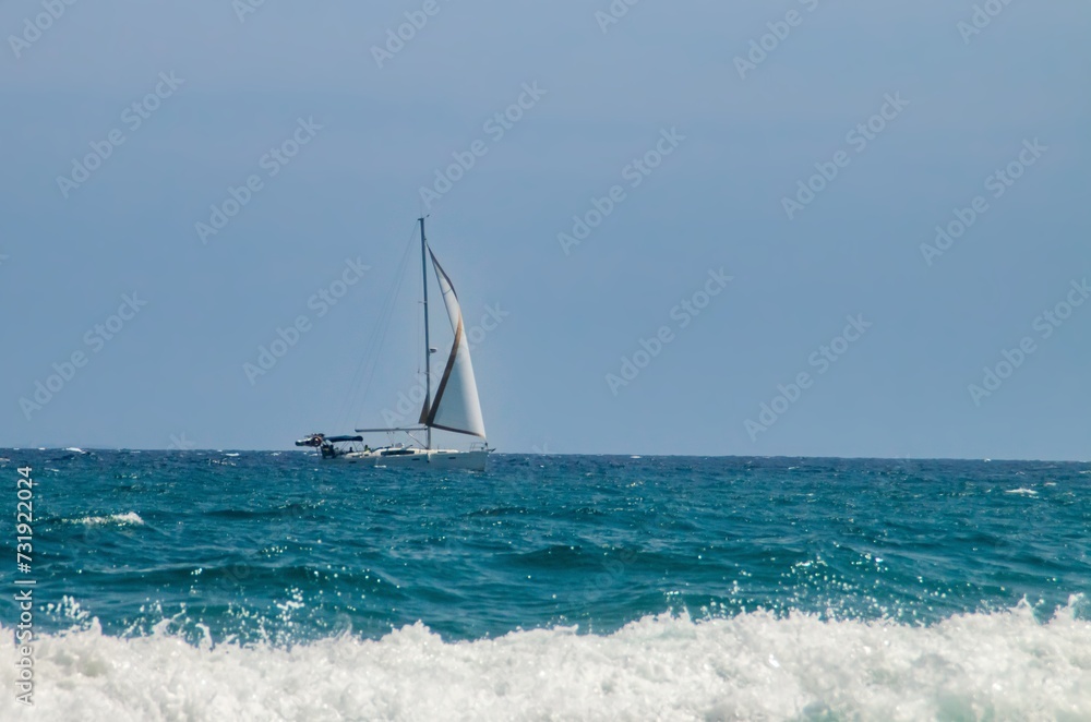 Velero navegando en el horizonte en cabo de Gata, España. Yate a toda vela navegando en las aguas turquesas del Mar Mediterráneo.