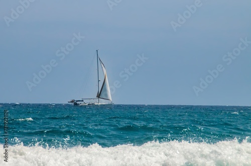 Velero navegando en el horizonte en cabo de Gata, España. Yate a toda vela navegando en las aguas turquesas del Mar Mediterráneo. © AngelLuis