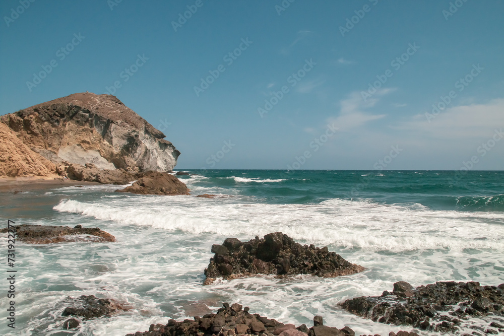 Acantilados, rocas y oleaje en la costa del mar Mediterráneo en un día despejado. Costa de cabo de Gata, cala de los amarillos en verano, Almería, España.