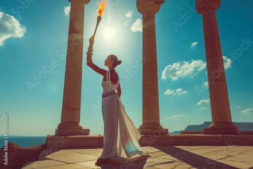 A woman in an ancient Greek peplos dress holds the Olympic flame photo