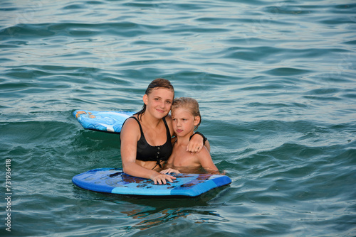 Two children with a swimming board in the water