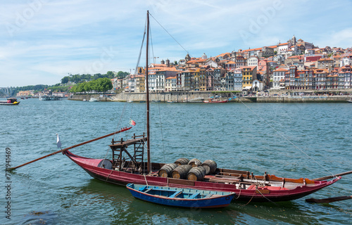 Viejo barco para el transporte de vino en el muelle de Vila Nova de Gaia y el histórico barrio de Ribeira al fondo, en Oporto, Portugal